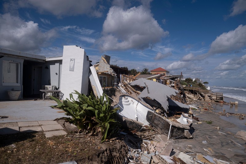 WILBUR-BY-THE-SEA, FLORIDA, UNITED STATES - NOVEMBER 11: A man walks past homes that collapsed onto the beach due to the storm surge and resulting erosion caused by Hurricane Nicole on November 11, 2022 in Wilbur-By-The-Sea, Florida. Nicole made landfall as a Category 1 hurricane before weakening into a tropical storm. (Photo by Paul Hennessy/Anadolu Agency via Getty Images)