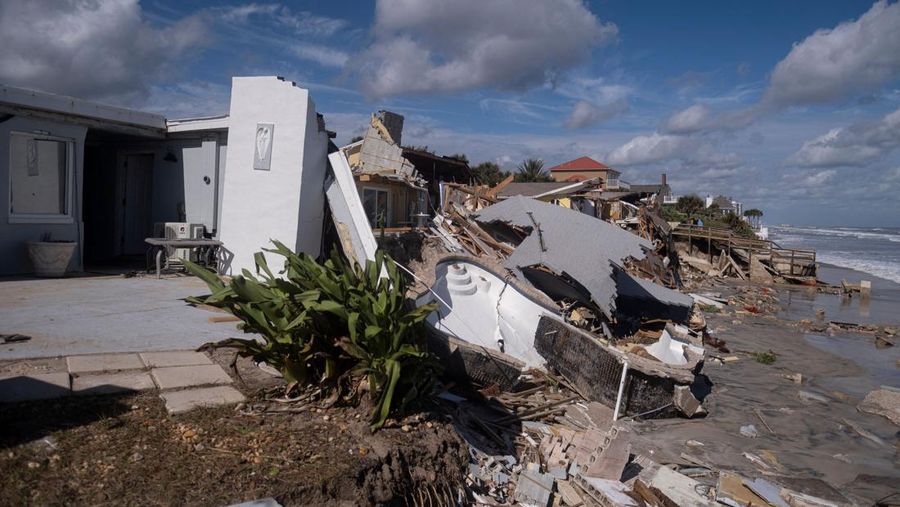 WILBUR-BY-THE-SEA, FLORIDA, UNITED STATES - NOVEMBER 11: A man walks past homes that collapsed onto the beach due to the storm surge and resulting erosion caused by Hurricane Nicole on November 11, 2022 in Wilbur-By-The-Sea, Florida. Nicole made landfall as a Category 1 hurricane before weakening into a tropical storm. (Photo by Paul Hennessy/Anadolu Agency via Getty Images)