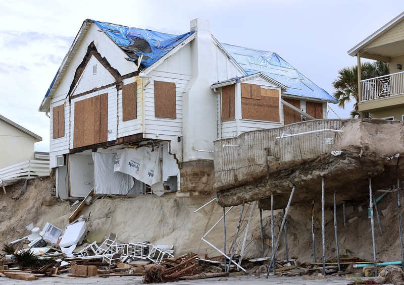 WILBUR-BY-THE-SEA, FLORIDA, UNITED STATES - NOVEMBER 11: A man walks past homes that collapsed onto the beach due to the storm surge and resulting erosion caused by Hurricane Nicole on November 11, 2022 in Wilbur-By-The-Sea, Florida. Nicole made landfall as a Category 1 hurricane before weakening into a tropical storm. (Photo by Paul Hennessy/Anadolu Agency via Getty Images)