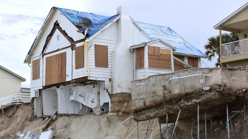 WILBUR-BY-THE-SEA, FLORIDA, UNITED STATES - NOVEMBER 11: A man walks past homes that collapsed onto the beach due to the storm surge and resulting erosion caused by Hurricane Nicole on November 11, 2022 in Wilbur-By-The-Sea, Florida. Nicole made landfall as a Category 1 hurricane before weakening into a tropical storm. (Photo by Paul Hennessy/Anadolu Agency via Getty Images)