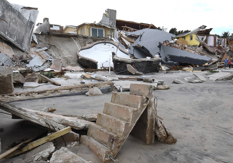 Rumah-rumah tepi pantai yang hancur setelah Badai Nicole di Pantai Daytona, Florida, pada 11 November 2022. WILBUR-BY-THE-SEA, FLORIDA, UNITED STATES - NOVEMBER 11: A man walks past homes that collapsed onto the beach due to the storm surge and resulting erosion caused by Hurricane Nicole on November 11, 2022 in Wilbur-By-The-Sea, Florida. Nicole made landfall as a Category 1 hurricane before weakening into a tropical storm. (Photo by Paul Hennessy/Anadolu Agency via Getty Images)