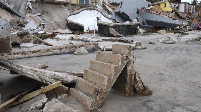 WILBUR-BY-THE-SEA, FLORIDA, UNITED STATES - NOVEMBER 11: A man walks past homes that collapsed onto the beach due to the storm surge and resulting erosion caused by Hurricane Nicole on November 11, 2022 in Wilbur-By-The-Sea, Florida. Nicole made landfall as a Category 1 hurricane before weakening into a tropical storm. (Photo by Paul Hennessy/Anadolu Agency via Getty Images)