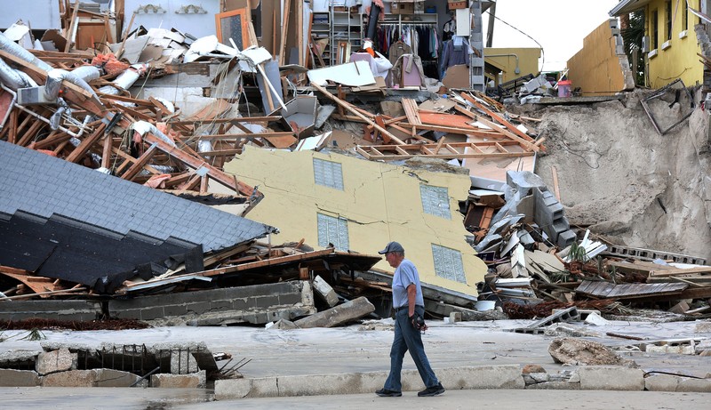 WILBUR-BY-THE-SEA, FLORIDA, UNITED STATES - NOVEMBER 11: A man walks past homes that collapsed onto the beach due to the storm surge and resulting erosion caused by Hurricane Nicole on November 11, 2022 in Wilbur-By-The-Sea, Florida. Nicole made landfall as a Category 1 hurricane before weakening into a tropical storm. (Photo by Paul Hennessy/Anadolu Agency via Getty Images)