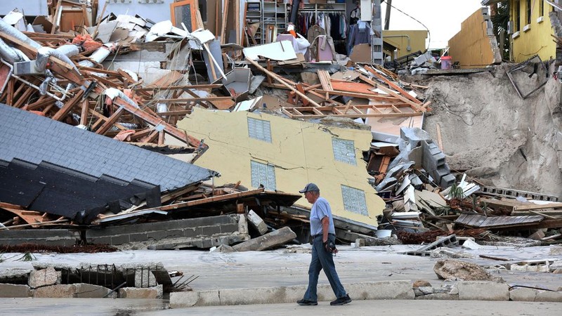 WILBUR-BY-THE-SEA, FLORIDA, UNITED STATES - NOVEMBER 11: A man walks past homes that collapsed onto the beach due to the storm surge and resulting erosion caused by Hurricane Nicole on November 11, 2022 in Wilbur-By-The-Sea, Florida. Nicole made landfall as a Category 1 hurricane before weakening into a tropical storm. (Photo by Paul Hennessy/Anadolu Agency via Getty Images)