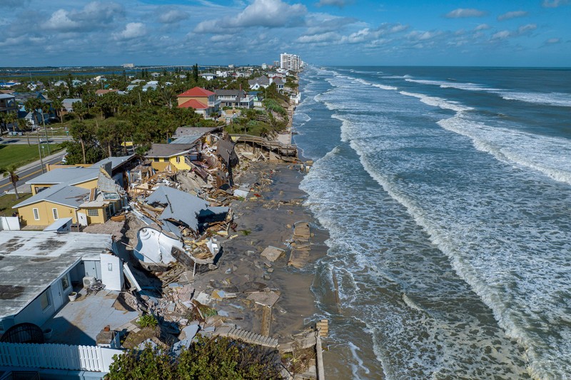 Rumah-rumah tepi pantai yang hancur setelah Badai Nicole di Pantai Daytona, Florida, pada 11 November 2022. WILBUR-BY-THE-SEA, FLORIDA, UNITED STATES - NOVEMBER 11: A man walks past homes that collapsed onto the beach due to the storm surge and resulting erosion caused by Hurricane Nicole on November 11, 2022 in Wilbur-By-The-Sea, Florida. Nicole made landfall as a Category 1 hurricane before weakening into a tropical storm. (Photo by Paul Hennessy/Anadolu Agency via Getty Images)