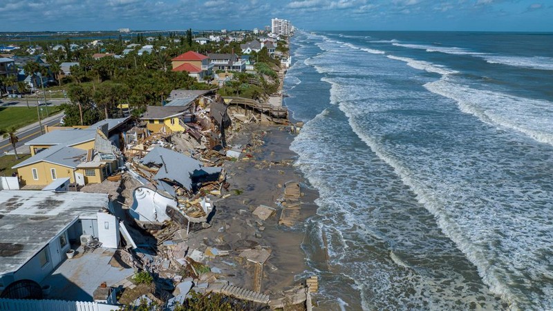 WILBUR-BY-THE-SEA, FLORIDA, UNITED STATES - NOVEMBER 11: A man walks past homes that collapsed onto the beach due to the storm surge and resulting erosion caused by Hurricane Nicole on November 11, 2022 in Wilbur-By-The-Sea, Florida. Nicole made landfall as a Category 1 hurricane before weakening into a tropical storm. (Photo by Paul Hennessy/Anadolu Agency via Getty Images)