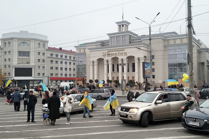 People hold Ukrainian flags as they gather to celebrate the liberation of their town in Kherson, on November 12, 2022, amid Russia's invasion of Ukraine. - On November 11, 2022, Russia said it had pulled back more than 30,000 troops in the southern region, with Ukrainian President Volodymyr Zelensky declaring Kherson 