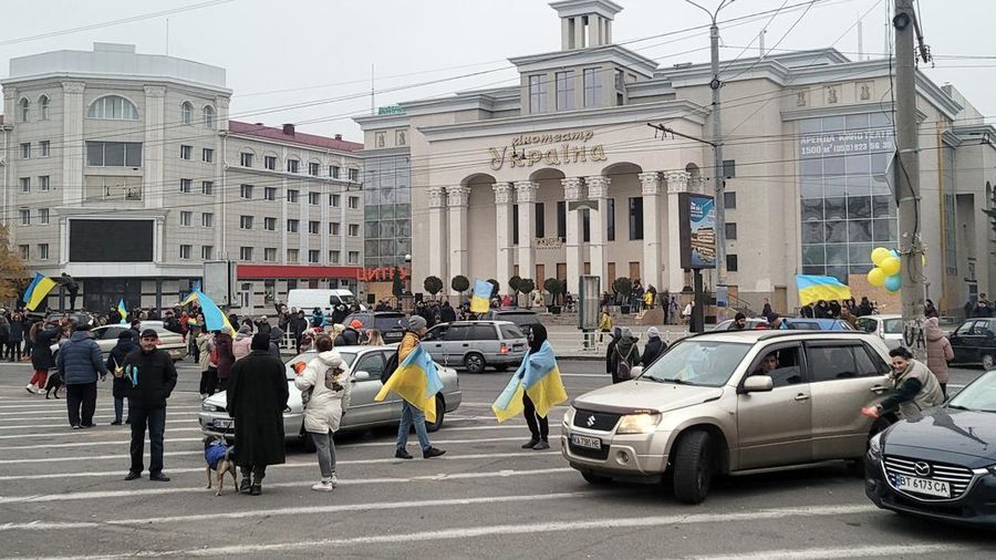 People hold Ukrainian flags as they gather to celebrate the liberation of their town in Kherson, on November 12, 2022, amid Russia's invasion of Ukraine. - On November 11, 2022, Russia said it had pulled back more than 30,000 troops in the southern region, with Ukrainian President Volodymyr Zelensky declaring Kherson 
