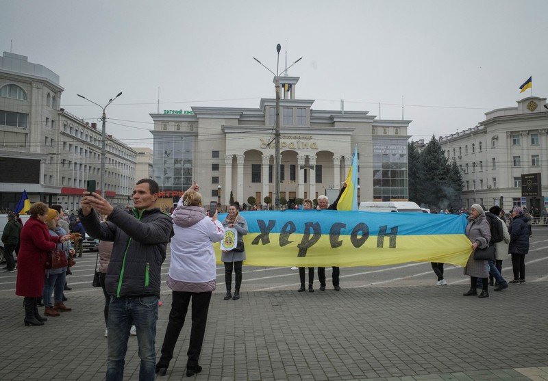1244739977 People hold Ukrainian flags as they gather to celebrate the liberation of their town in Kherson, on November 12, 2022, amid Russia's invasion of Ukraine. - On November 11, 2022, Russia said it had pulled back more than 30,000 troops in the southern region, with Ukrainian President Volodymyr Zelensky declaring Kherson
