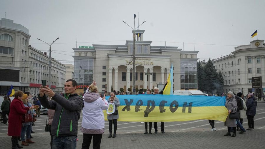 People hold Ukrainian flags as they gather to celebrate the liberation of their town in Kherson, on November 12, 2022, amid Russia's invasion of Ukraine. - On November 11, 2022, Russia said it had pulled back more than 30,000 troops in the southern region, with Ukrainian President Volodymyr Zelensky declaring Kherson 