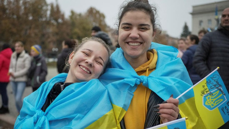 People hold Ukrainian flags as they gather to celebrate the liberation of their town in Kherson, on November 12, 2022, amid Russia's invasion of Ukraine. - On November 11, 2022, Russia said it had pulled back more than 30,000 troops in the southern region, with Ukrainian President Volodymyr Zelensky declaring Kherson 
