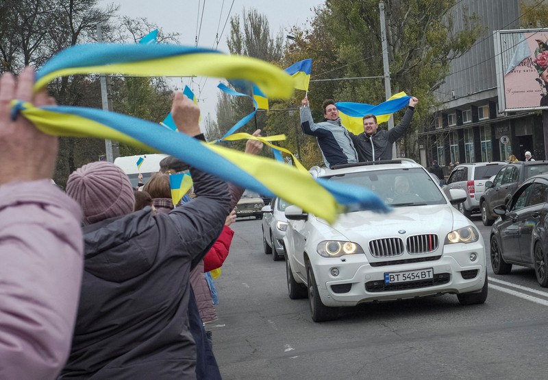 1244739977 People hold Ukrainian flags as they gather to celebrate the liberation of their town in Kherson, on November 12, 2022, amid Russia's invasion of Ukraine. - On November 11, 2022, Russia said it had pulled back more than 30,000 troops in the southern region, with Ukrainian President Volodymyr Zelensky declaring Kherson
