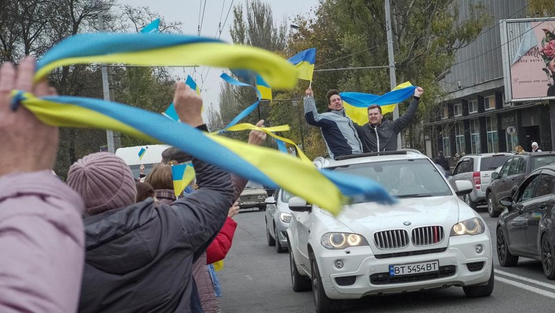 People hold Ukrainian flags as they gather to celebrate the liberation of their town in Kherson, on November 12, 2022, amid Russia's invasion of Ukraine. - On November 11, 2022, Russia said it had pulled back more than 30,000 troops in the southern region, with Ukrainian President Volodymyr Zelensky declaring Kherson 