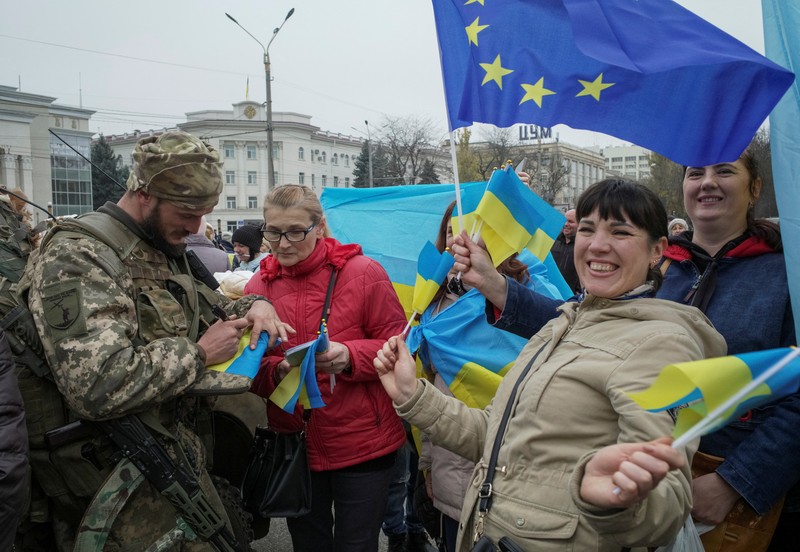 People hold Ukrainian flags as they gather to celebrate the liberation of their town in Kherson, on November 12, 2022, amid Russia's invasion of Ukraine. - On November 11, 2022, Russia said it had pulled back more than 30,000 troops in the southern region, with Ukrainian President Volodymyr Zelensky declaring Kherson 