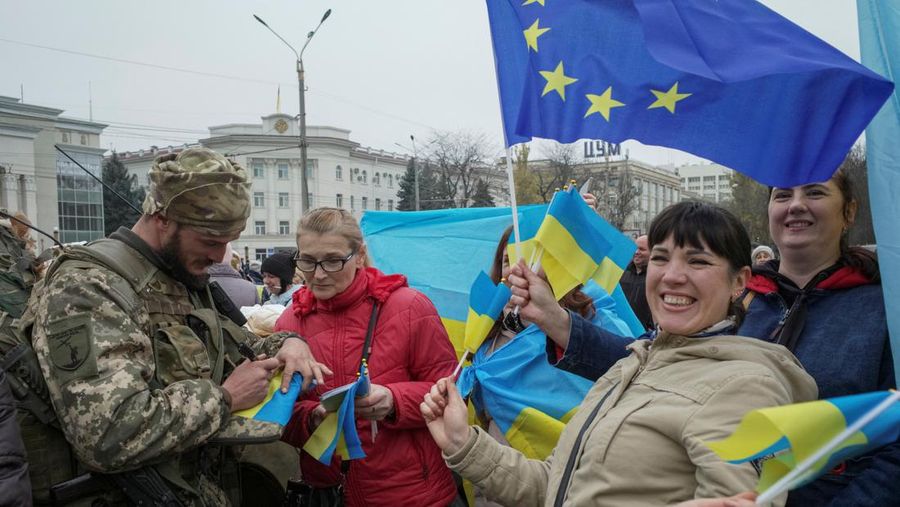 People hold Ukrainian flags as they gather to celebrate the liberation of their town in Kherson, on November 12, 2022, amid Russia's invasion of Ukraine. - On November 11, 2022, Russia said it had pulled back more than 30,000 troops in the southern region, with Ukrainian President Volodymyr Zelensky declaring Kherson 