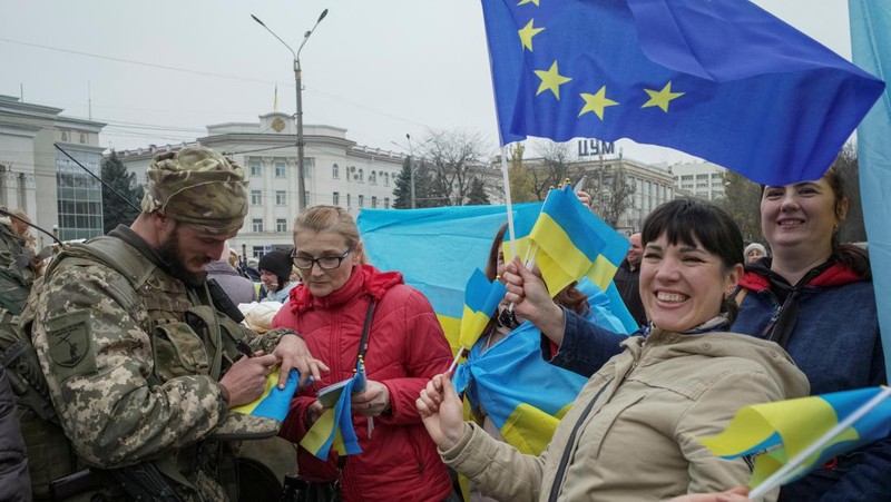 People hold Ukrainian flags as they gather to celebrate the liberation of their town in Kherson, on November 12, 2022, amid Russia's invasion of Ukraine. - On November 11, 2022, Russia said it had pulled back more than 30,000 troops in the southern region, with Ukrainian President Volodymyr Zelensky declaring Kherson 
