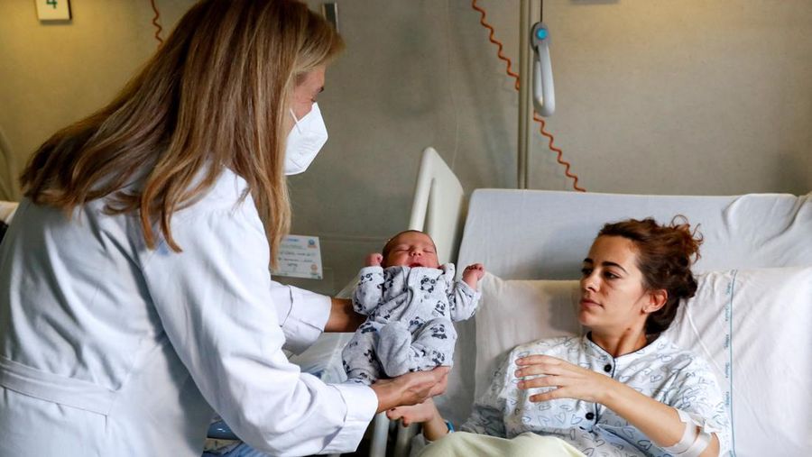 Newborn baby Leonardo is held by a doctor next to his mom, Viviana Valente, inside a room of the Santo Spirito Hospital, as the UN forecasts the world will reach 8 billion people around November 15, 2022, in Rome, Italy, November 14, 2022. REUTERS/Remo Casilli