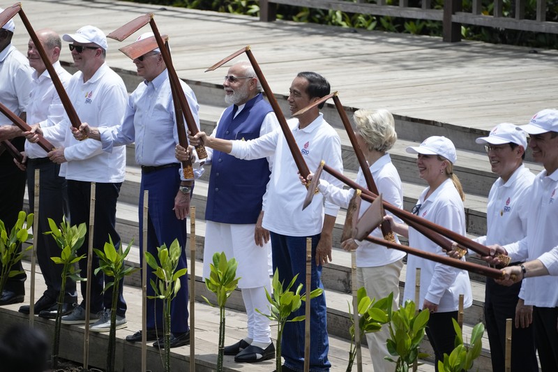 Biden G20 Leaders raise their garden hoes for a group photo during a tree planting event at the Taman Hutan Raya Ngurah Rai Mangrove Forest, on the sidelines of the G20 summit meeting, Wednesday, Nov. 16, 2022, in Denpasar, Bali, Indonesia. (AP Photo/Alex Brandon, Pool)