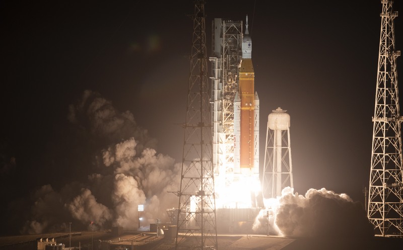 Artemis 1 mengirimkan pesawat ruang angkasa Orion baru NASA dalam uji terbang tanpa awak mengelilingi bulan. People at Veterans Memorial park watch as the Artemis I unmanned lunar rocket lifts off from launch pad 39B at NASA's Kennedy Space Center, in Titusville, Florida, on November 16, 2022. - NASA's Artemis 1 mission is a 25-and-a-half day voyage beyond the far side of the Moon and back. The meticulously choreographed uncrewed flight should yield spectacular images as well as valuable scientific data. (Photo by Marco BELLO / AFP) (Photo by MARCO BELLO/AFP via Getty Images)