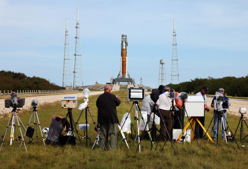 Artemis 1 mengirimkan pesawat ruang angkasa Orion baru NASA dalam uji terbang tanpa awak mengelilingi bulan. People at Veterans Memorial park watch as the Artemis I unmanned lunar rocket lifts off from launch pad 39B at NASA's Kennedy Space Center, in Titusville, Florida, on November 16, 2022. - NASA's Artemis 1 mission is a 25-and-a-half day voyage beyond the far side of the Moon and back. The meticulously choreographed uncrewed flight should yield spectacular images as well as valuable scientific data. (Photo by Marco BELLO / AFP) (Photo by MARCO BELLO/AFP via Getty Images)