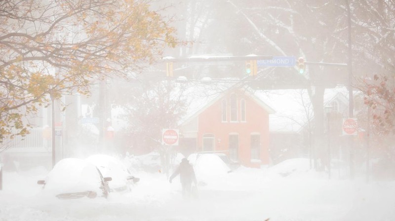 Seseorang berjalan di jalan selama badai salju saat cuaca musim dingin yang ekstrem melanda Buffalo, New York, AS, Sabtu (19/11/2022). Badai salju tersebut menyebabkan dua orang tewas, perjalanan terganggu dan timbunan es tinggi selama akhir pekan. (REUTERS/Lindsay DeDario)