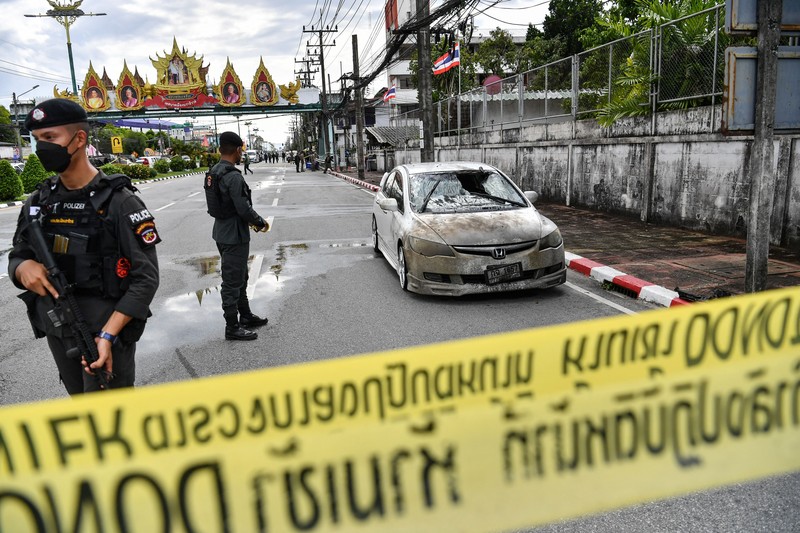 Sebuah bom mobil meledak di dalam kompleks kantor polisi di wilayah Thailand bagian selatan. Sedikitnya satu orang tewas dan puluhan orang lainnya mengalami luka-luka akibat ledakan ini. Police officials stand near a partly damaged car, after a car bomb exploded outside a police accommodation in Narathiwat town, southern Thailand, on November 22, 2022. - One person died and more than two dozen were injured in the attack, the provincial governor said. (Photo by MADAREE THOLALA / AFP) (Photo by MADAREE THOLALA/AFP via Getty Images)