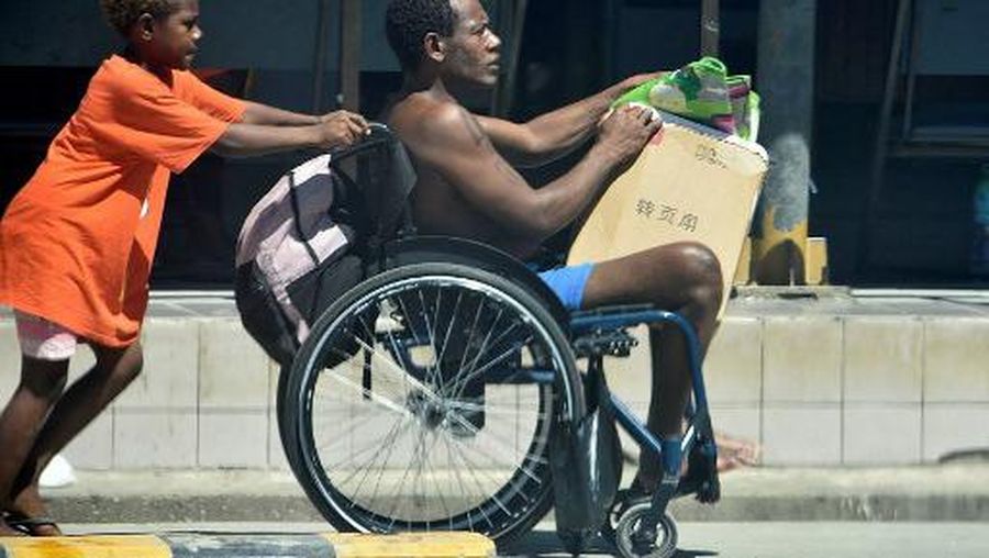A boy pushes the wheelchair of a family member in downtown of Honiara on November 22, 2022, as people rushed from their offices and fleeing to higher ground after a strong earthquake. - A strong 7.0 magnitude earthquake struck the Solomon Islands with eyewitnesses reporting violent shaking that hurled items to the ground and knocked out power in parts of the capital Honiara. (Photo by Mavis PODOKOLO / AFP)