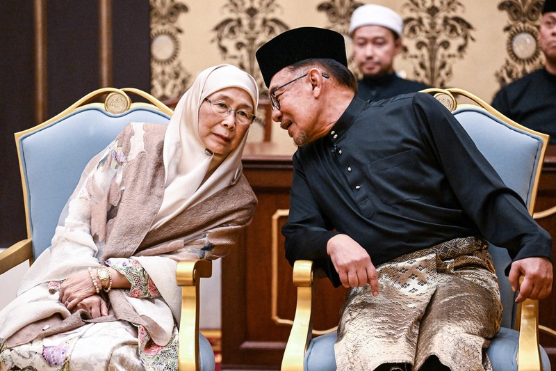 Perdana Menteri Malaysia yang baru diangkat Anwar Ibrahim (kanan) dan istrinya Wan Azizah Wan Ismail (kiri) pergi setelah upacara pengambilan sumpah di Istana Nasional di Kuala Lumpur pada 24 November 2022. (FAZRY ISMAIL/POOL/AFP via Getty Images )