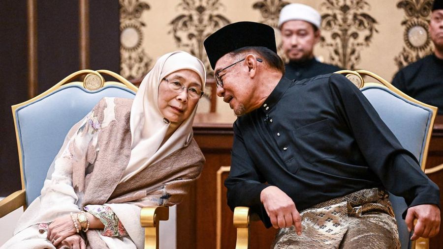 Perdana Menteri Malaysia yang baru diangkat Anwar Ibrahim (kanan) dan istrinya Wan Azizah Wan Ismail (kiri) pergi setelah upacara pengambilan sumpah di Istana Nasional di Kuala Lumpur pada 24 November 2022. (FAZRY ISMAIL/POOL/AFP via Getty Images )