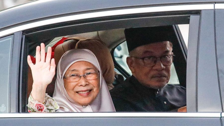 Perdana Menteri Malaysia yang baru diangkat Anwar Ibrahim (kanan) dan istrinya Wan Azizah Wan Ismail (kiri) pergi setelah upacara pengambilan sumpah di Istana Nasional di Kuala Lumpur pada 24 November 2022. (FAZRY ISMAIL/POOL/AFP via Getty Images )