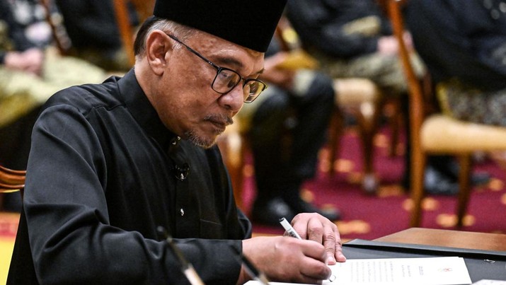 Perdana Menteri Malaysia yang baru diangkat Anwar Ibrahim menandatangani dokumen setelah mengambil sumpah selama upacara pengambilan sumpah di Istana Nasional di Kuala Lumpur pada 24 November 2022. (MOHD RASFAN/POOL/AFP via Getty Images)