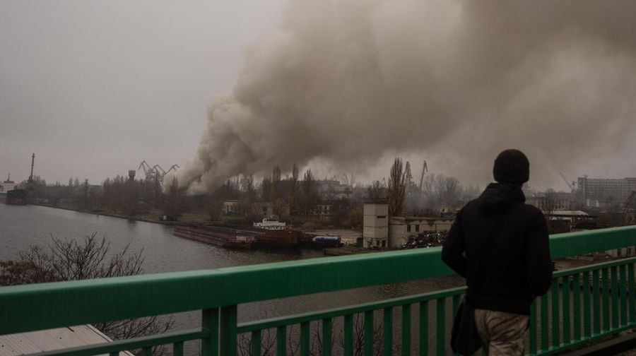 Seorang pria melihat asap mengepul dari serangan Rusia di galangan kapal Kherson pada 24 November 2022 di Kherson, Ukraina. Pasukan Ukraina menguasai Kherson dalam beberapa pekan terakhir, serta petak wilayah sekitarnya, setelah Rusia menarik pasukannya kembali ke sisi lain sungai Dnipro. Kherson adalah satu-satunya ibu kota regional yang direbut oleh Rusia setelah invasinya pada 24 Februari. (Chris McGrath/Getty Images)