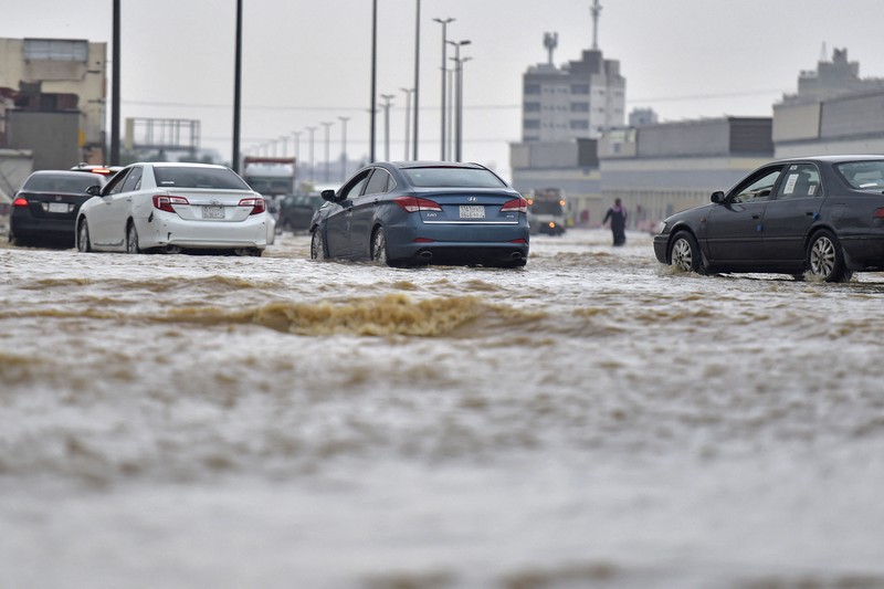 Mobil melewati jalan yang banjir setelah hujan lebat di kota pesisir Saudi Jeddah pada 24 November 2022, yang menunda penerbangan, memaksa penangguhan sekolah dan menutup jalan ke Mekah, kota paling suci bagi umat Islam. - Jeddah, kota berpenduduk sekitar empat juta orang yang terletak di Laut Merah, sering disebut sebagai 