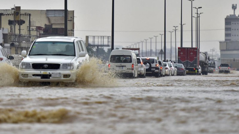 Mobil melewati jalan yang banjir setelah hujan lebat di kota pesisir Saudi Jeddah pada 24 November 2022, yang menunda penerbangan, memaksa penangguhan sekolah dan menutup jalan ke Mekah, kota paling suci bagi umat Islam. - Jeddah, kota berpenduduk sekitar empat juta orang yang terletak di Laut Merah, sering disebut sebagai 