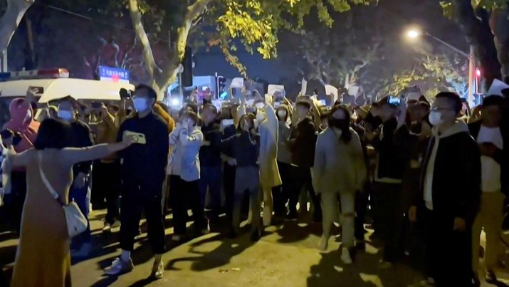 Petugas polisi mengkondusifkan para pendemo selama protes terhadap pembatasan penyakit coronavirus (COVID-19) di Shanghai, Cina, 27 November 2022, dalam tangkapan layar yang diperoleh dari video media sosial. This frame grab from eyewitness video footage made available via AFPTV on November 27, 2022 shows demonstrators shouting slogans in Shanghai. - Angry crowds took to the streets in Shanghai in the early hours of November 27 and videos on social media showed protests in other cities across China, as public opposition to the government's hardline zero-Covid policy mounts. (-/AFPTV/AFP via Getty Images)