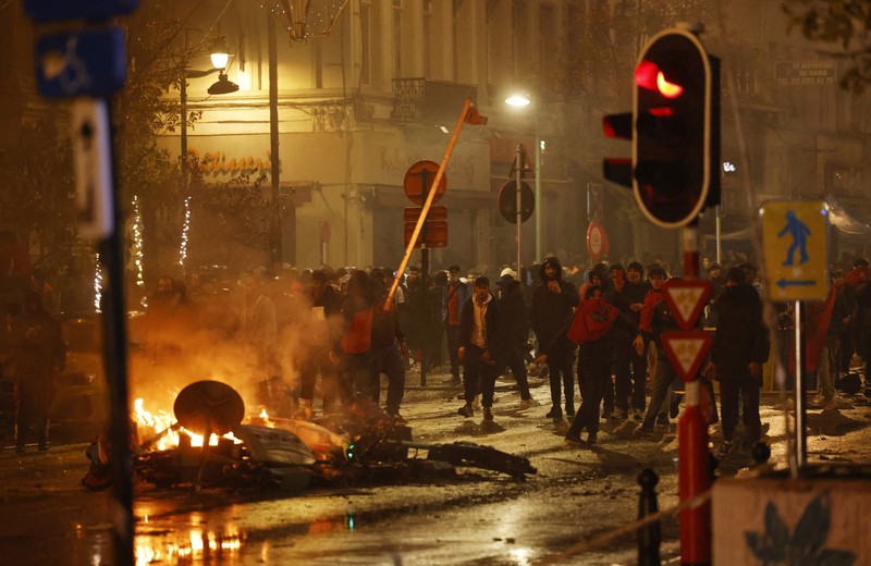 Seorang pria dengan wajah tertutup dan alat pemadam api terlihat selama bentrokan usai pertandingan Piala Dunia antara Belgia dan Maroko di Brussel, Belgia, Minggu (27/11/2022). Bentrokan terjadi di Kota Brussel usai Timnas Belgia kalah dari Maroko 2-0 di Piala Dunia Qatar. Para suporter menyalakan api dan melemparkan petasan ke polisi. (REUTERS/Yves Herman)