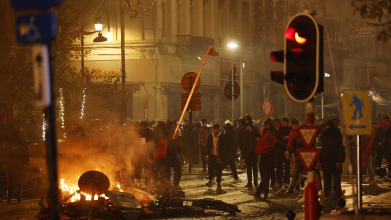 Seorang pria dengan wajah tertutup dan alat pemadam api terlihat selama bentrokan usai pertandingan Piala Dunia antara Belgia dan Maroko di Brussel, Belgia, Minggu (27/11/2022). Bentrokan terjadi di Kota Brussel usai Timnas Belgia kalah dari Maroko 2-0 di Piala Dunia Qatar. Para suporter menyalakan api dan melemparkan petasan ke polisi. (REUTERS/Yves Herman)