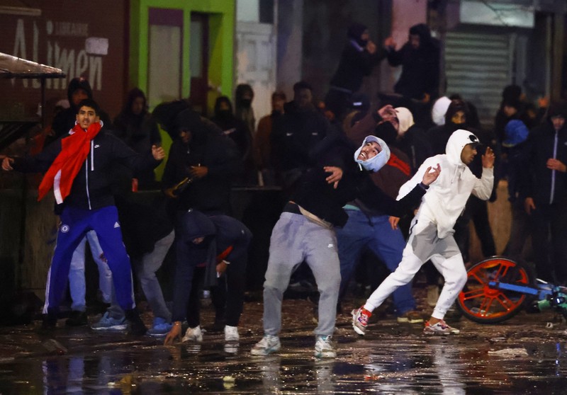 Bentrokan Suporter dengan Polisi di Brussel, Belgia Usai Pertandingan piala dunia antara Belgia dan Maroko Seorang pria dengan wajah tertutup dan alat pemadam api terlihat selama bentrokan usai pertandingan Piala Dunia antara Belgia dan Maroko di Brussel, Belgia, Minggu (27/11/2022). Bentrokan terjadi di Kota Brussel usai Timnas Belgia kalah dari Maroko 2-0 di Piala Dunia Qatar. Para suporter menyalakan api dan melemparkan petasan ke polisi. (REUTERS/Yves Herman)