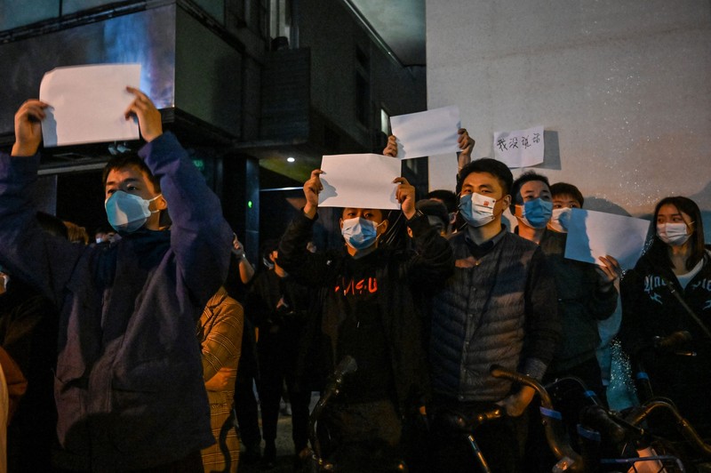 Para pengunjuk rasa mengangkat selembar kertas putih menentang pembatasan gerak akibat penyebaran virus corona (COVID-19) di Beijing, Sabtu (27/11/2022). Protes tersebut terjadi usai kebakaran yang terjadi pada 24 November 2022 di Urumqi, ibu kota wilayah Xinjiang China barat laut yang menimbukan kemarahan publik yang menyalahkan penguncian akibat virus corona karena menghambat upaya penyelamatan. Aksi demo di China termasuk kejadian yang cukup langka, yang belum pernah terjadi sebelumnya sejak Xi Jinping mengambil alih kekuasaan satu dekade lalu. (Photo by Kevin Frayer/Getty Images)