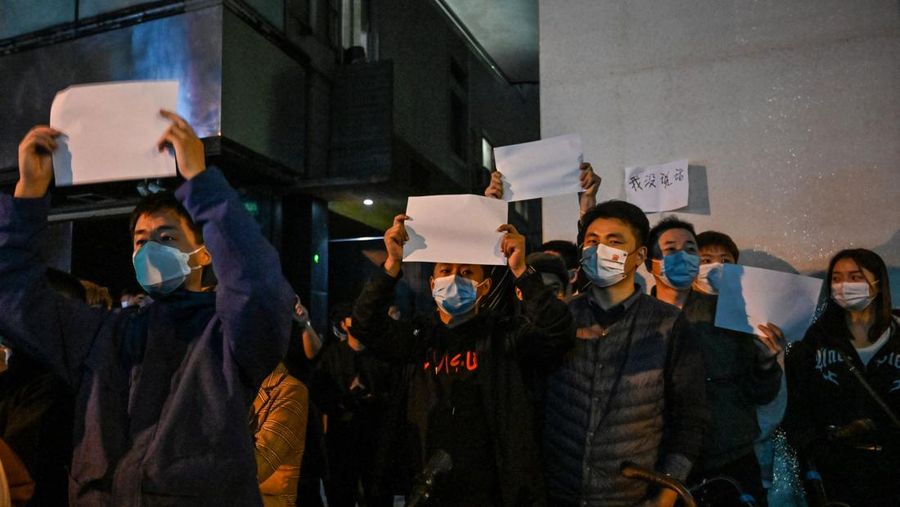 Para pengunjuk rasa mengangkat selembar kertas putih menentang pembatasan gerak akibat penyebaran virus corona (COVID-19) di Beijing, Sabtu (27/11/2022). Protes tersebut terjadi usai kebakaran yang terjadi pada 24 November 2022 di Urumqi, ibu kota wilayah Xinjiang China barat laut yang menimbukan kemarahan publik yang menyalahkan penguncian akibat virus corona karena menghambat upaya penyelamatan. Aksi demo di China termasuk kejadian yang cukup langka, yang belum pernah terjadi sebelumnya sejak Xi Jinping mengambil alih kekuasaan satu dekade lalu. (Photo by Kevin Frayer/Getty Images)