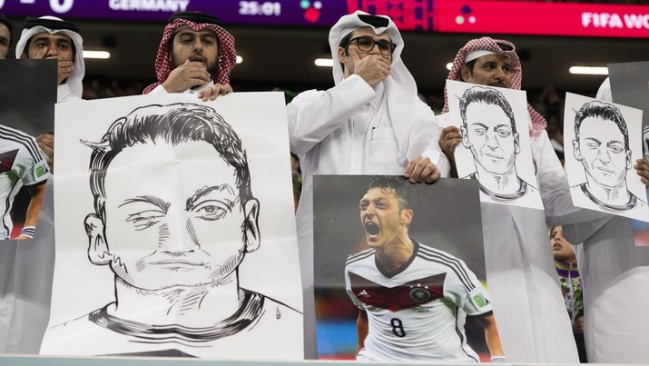 Orang-orang di tribun memegang potret pemain sepak bola Jerman Mesut zil dalam protes terhadap diskriminasi Uighur di China selama pertandingan Grup E Piala Dunia FIFA Qatar 2022 antara Spanyol dan Jerman di Stadion Al Bayt pada 27 November 2022 di Al Khor, Qatar. (Sebastian Frej/MB Media/Getty Images)