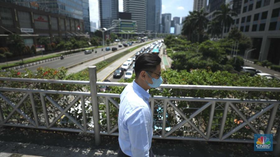Sejumlah karyawan melewati jembatan penyeberangan orang (JPO) di kawasan Sudirman, Jakarta, Selasa (29/11/2022). Kepala Disnakertrans provinsi DKI Jakarta Andri Yansyah mengungkapkan kenaikan UMP 2023 DKI Jakarta sebesar 5,6% ke Rp 4.901.798.  (CNBC Indonesia/Tri Susilo)