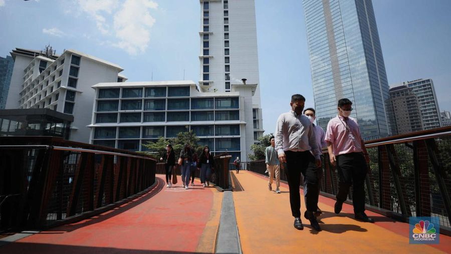 Sejumlah karyawan melewati jembatan penyeberangan orang (JPO) di kawasan Sudirman, Jakarta, Selasa (29/11/2022). Kepala Disnakertrans provinsi DKI Jakarta Andri Yansyah mengungkapkan kenaikan UMP 2023 DKI Jakarta sebesar 5,6% ke Rp 4.901.798.  (CNBC Indonesia/Tri Susilo)