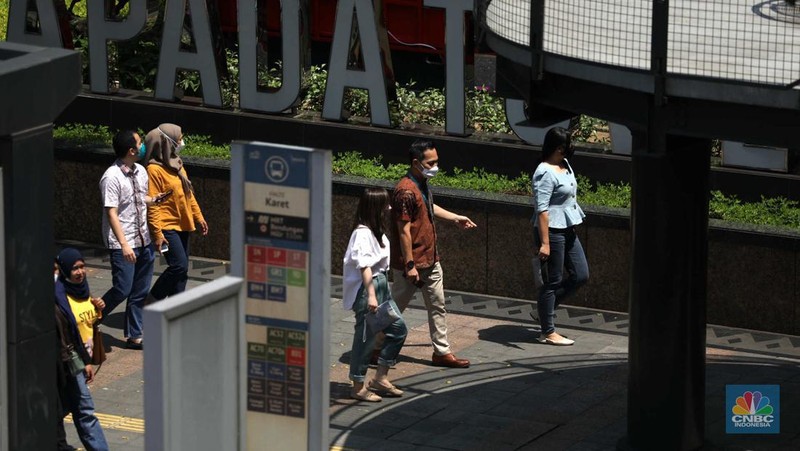 Sejumlah karyawan melewati jembatan penyeberangan orang (JPO) di kawasan Sudirman, Jakarta, Selasa (29/11/2022). Kepala Disnakertrans provinsi DKI Jakarta Andri Yansyah mengungkapkan kenaikan UMP 2023 DKI Jakarta sebesar 5,6% ke Rp 4.901.798.  (CNBC Indonesia/Tri Susilo)