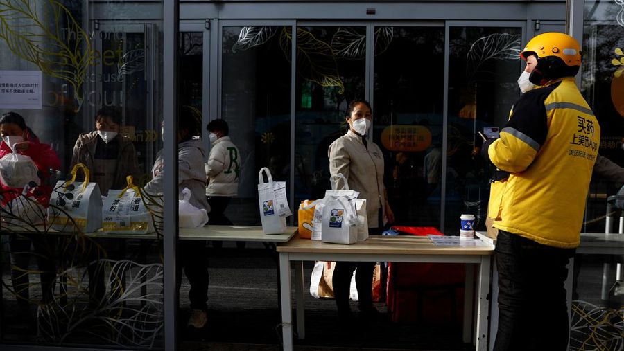 Seorang wanita mengantarkan makanan ke kompleks perumahan yang dikunci karena wabah penyakit virus corona (COVID-19) berlanjut di Beijing, China, Senin (28/11/2022). Kota-kota di Cina semakin banyak yang memberlakukan lockdown lokal menyusul naiknya kasus harian positif Covid-19. Komisi Kesehatan Nasional China melaporkan pada Senin (28/11) waktu setempat bahwa sedikitnya 40.052 kasus Corona tercatat dalam sehari, secara nasional di negara tersebut. (REUTERS/Thomas Peter)