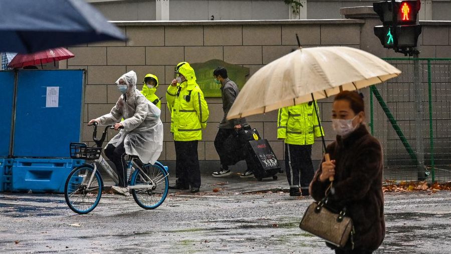 Polisi (berbaju kuning) berjaga di jalan Wulumuqi, dinamai Urumqi dalam bahasa Mandarin, di Shanghai pada 29 November 2022, dua hari setelah protes yang jarang terjadi terhadap kebijakan nol-Covid China menyusul kebakaran mematikan di Urumqi, ibu kota wilayah Xinjiang.