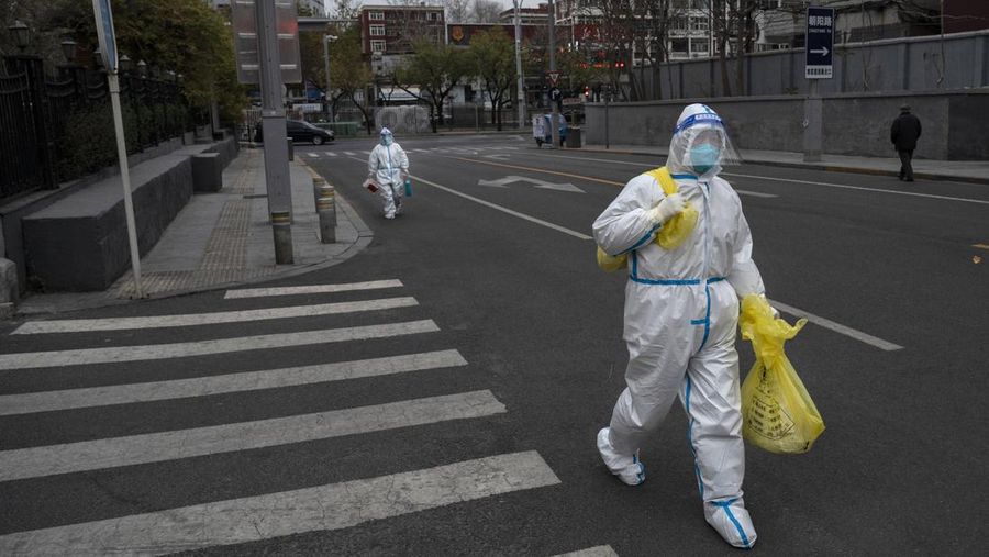 Pekerja pengendalian epidemi mengenakan APD untuk melindungi dari penyebaran COVID-19 saat mereka berjalan di jalan setelah melakukan tes asam nukleat atau swab test pada penduduk lokal di Beijing, China, Senin (28/11/2022). Kota-kota di Cina semakin banyak yang memberlakukan lockdown lokal menyusul naiknya kasus harian positif Covid-19. Komisi Kesehatan Nasional China melaporkan pada Senin (28/11) waktu setempat bahwa sedikitnya 40.052 kasus Corona tercatat dalam sehari, secara nasional di negara tersebut. (Photo by Kevin Frayer/Getty Images)
