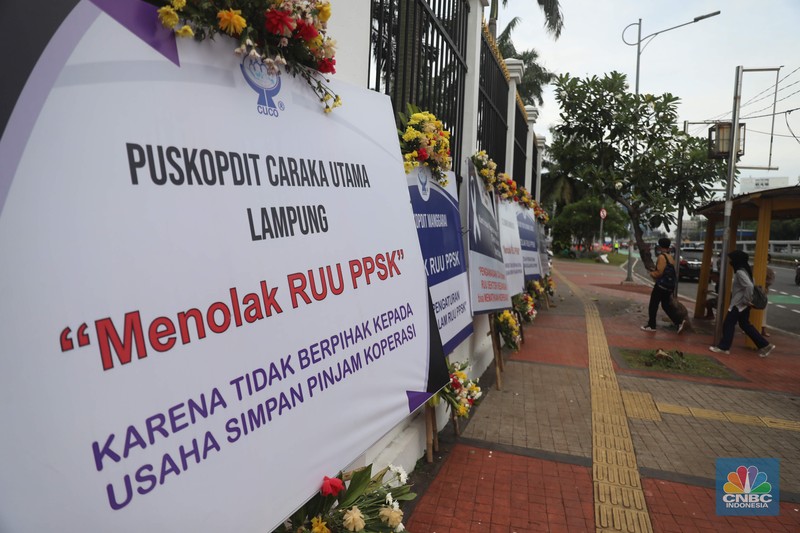 karangan bunga berisi penolakan rancangan undang-undang (RUU) penguatan, pengembangan sektor keuangan (PPSK) berjejer di depan gedung DPR/MPR Sejumlah karangan bunga berisi penolakan rancangan undang-undang (RUU) penguatan, pengembangan sektor keuangan (PPSK) berjejer di depan gedung DPR/MPR, Jakarta, Rabu (30/11/2022). Puluhan karangan bunga berisi penolakan rancangan undang-undang (RUU) penguatan, pengembangan sektor keuangan (PPSK) memenuhi pagar depan gedung Dewan Perwakilan Rakyat Republik Indonesia (DPR RI). (CNBC Indonesia/ Muhammad Sabki)