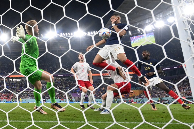 Penyerang Prancis, Kylian Mbappe mencetak gol kedua timnya usai melewati kiper Denmark, Kasper Schmeichel saat pertandingan Group D antara Prancis melawan Denmark pada laga Piala Dunia FIFA Qatar 2022 di Stadion 974, Doha, Qatar, Sabtu (26/11/2022). Prancis jadi tim pertama yang lolos ke Babak 16 Besar Piala Dunia 2022 setelah Les Bleus mengalahkan Denmark 2-1 berkat sepasang gol Kylian Mbappe. (Photo by FRANCK FIFE/AFP via Getty Images)