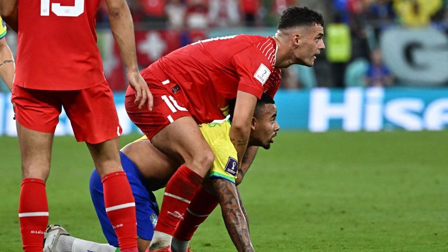 Gelandang Swiss, Granit Xhaka (Kiri) dan penyerang Brasil, Gabriel Jesus melihat bola selama pertandingan Grup G antara Brasil melawan Swiss pada laga Piala Dunia FIFA Qatar 2022 di Stadion 974, Doha, Qatar, Senin (28/11/2022). Brasil berhasil mengalahkan Swiss 1-0 dalam matchday kedua Grup G Piala Dunia 2022. Hasil ini mengantarkan Brasil lolos ke babak 16 besar, mengikuti jejak Prancis yang lebih dulu melaju. (Photo by ANNE-CHRISTINE POUJOULAT/AFP via Getty Images)